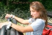 Stella tied and gagged in a grey shiny nylon catsuit in a car