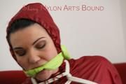 Jill tied, gagged and hooded on a red sofa wearing a black rainpants and a red rain jacket (Pics)