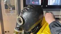 See Lady M, bound in shiny yellow Rainsuit, wearing a latex Mask and a Gasmask