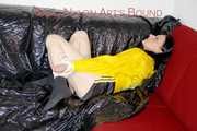 LUCY tied and gagged with ropes and a ballgag on a sofa wearing a sexy black/yellow shiny nylon shorts and a yellow rain jacket (Pics)