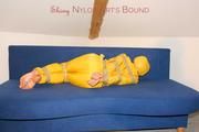 Archive girl tied and gagged by using tape on a sofa wearing an yellow rainsuit (Pics)