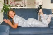 Stella posing in a living room wearing a supersexy grey rainwear jumpsuit (Pics)