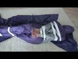 A video with Alina tied and gagged in a shiny purple and silver PVC suit