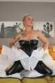 Busty blonde Frida posing in white shirt, leather corsage and black glossy leggins on bed
