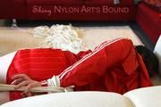 Jill tied and gagged lying on a sofa wearing a sexy shiny red adidas shorts and a red rain jacket (Pics)