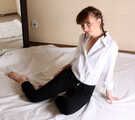 Topless barefoot Polina in unbuttoned white shirt and black jeans, bound with red ropes, poses on the floor
