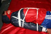 Alina bound in blue shorts and a shiny jacket