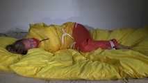 Watching Sandra  wearing an orange shiny nylon rain pants and a yellow shiny nylon rain jacket being tied and gagged on a bed with ropes and a clothgag (Video)