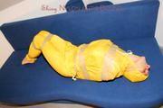 Archive girl tied and gagged by using tape on a sofa wearing an yellow rainsuit (Pics)