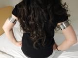 Oval metal rings squeezing Ranias soft upper arms