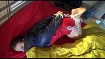 Jill tied and gagged on a bed wearing an sexy shiny nylon shorts and an oldschool rain jacket (Video)