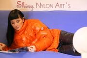 Mara wearing a sexy black down pants and an orange down jacket while lolling and reading on the sofa (Pics)