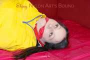 ***LUCIE*** wearing red/yellow shiny nylon shorts and a yellow shiny nylon rain jacket being bound on a sofa with ropes and a ball gag (Pics)
