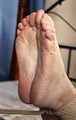 Ballgagged barefoot Carolyn, hogtied with hemp rope, wiggles on the bed