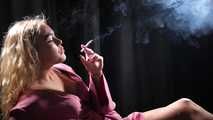 Blonde girl is smoking a cigarette is the dark room