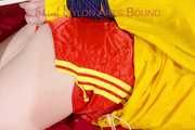 ***LUCIE*** wearing red/yellow shiny nylon shorts and a yellow shiny nylon rain jacket being bound on a sofa with ropes and a ball gag (Pics)