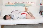 JIll tied and gagged on a white sofa wearing a sexy white/red shiny nylon shorts and a white rain jacket (Pics)