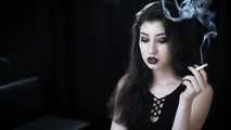 Goth girl with black eyes occasionally prefers dragging a 120mm cigarette
