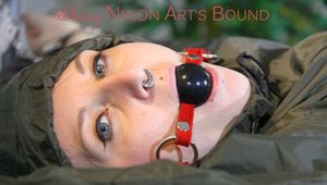 Mara wearing supersexy green rainwear tied on bed with cuffs and gagged with a ball gag (Pics)