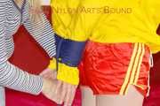***LUCIE*** wearing red/yellow shiny nylon shorts and a yellow shiny nylon rain jacket being bound on a sofa with ropes and a ball gag (Pics)