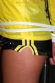Alina tied and gagged to a pole in nylon shorts and yellow cagoule