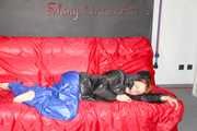 Sonja wearing a blue shiny nylon raver pants and a black down jacket posing and lollingn on the sofa (Pics)