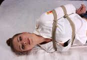 Barefoot Lisa in white shirt and jeans shorts, hogtied with hemp rope, wiggles and rolls on the bed