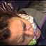 Lulu tied and gagged on a bed wearing a sexy purple shiny nylon shorts and a purple/grey shiny nylon rain jacket (Video)