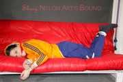 Lucy tied and gagged on a sofa wearing an orange shiny nylon rain jacket and a blue rain pants (Pics)
