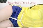 Mara tied and gagged with ropes and cloth gag on a sofa wearing a sexy blue shiny nylon shorts and a yellow/black oldschool rain jacket (Pics)