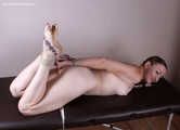 Nude barefoot Amanda, hogtied with hemp rope on the massage couch, is spanked and teased by a camera man