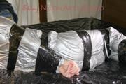 Pia tied and gagged with tape on a bed wearing a sexy silver rainwear combination (Pics) 