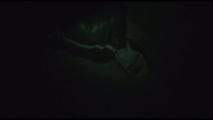 Jill tied, gagged and hooded on a cellar floor wearing a shiny green rain pants and a shiny black down jacket (Video)