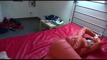 Mara tied and gagged on bed wearing a sexy orange shiny down jacket and a orange rain pants (Video)