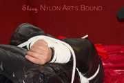 Lucy wearing a black shiny nylon rainh pants and a black down jacket tied and gagged on a sofa (Pics)