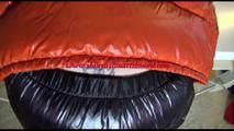 Mara tied and gagged on a table wearing a sexy black down pants and an orange down jacket (Video)