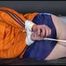 Lucy tied and gagged on a bed wearing a blue shiny nylon shorts and an orange shiny nylon rain jacket (Video)
