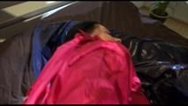 Lucy tied and gagged on bed wearing a darkred shiny nylon shorts and a red rain jacket (Video)