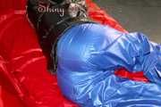 Sonja wearing a blue shiny nylon raver pants and a black down jacket posing and lollingn on the sofa (Pics)