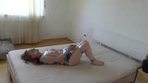 Maria in tape on bed 3/4