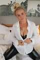 Busty blonde Frida posing in white shirt, leather corsage and black glossy leggins on bed