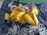 Archive girl tied and gagged on bed wearing a shiny yellow rainwear (Video)