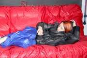 Sonja wearing a blue shiny nylon raver pants and a black down jacket posing and lollingn on the sofa (Pics)