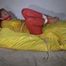 Watching Sandra  wearing an orange shiny nylon rain pants and a yellow shiny nylon rain jacket being tied and gagged on a bed with ropes and a clothgag (Video)