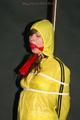Alina tied and gagged to a pole in nylon shorts and yellow cagoule