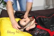 Lucy tied and gagged in a bed wearing a black shiny nylon downwear combination (Pics)