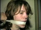 HEATHER IS F0RCED TO TAPE UP HER LEGS AND BARE FEET & IS THEN PANTY STUFFED AND WRAP GAGGED THEN HOG-TIED WITH TAPE ON THE BED (D52-14)