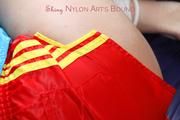 Pia tied and gagged on a bed wearing a shiny red nylon shorts and a blue rain jacket (Pics)