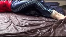 Mara tied, gagged and hooded on bed wearing s shiny red down jacket and a darkblue rain pants (Video)