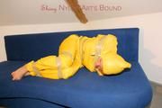 Archive girl tied and gagged by using tape on a sofa wearing an yellow rainsuit (Pics)